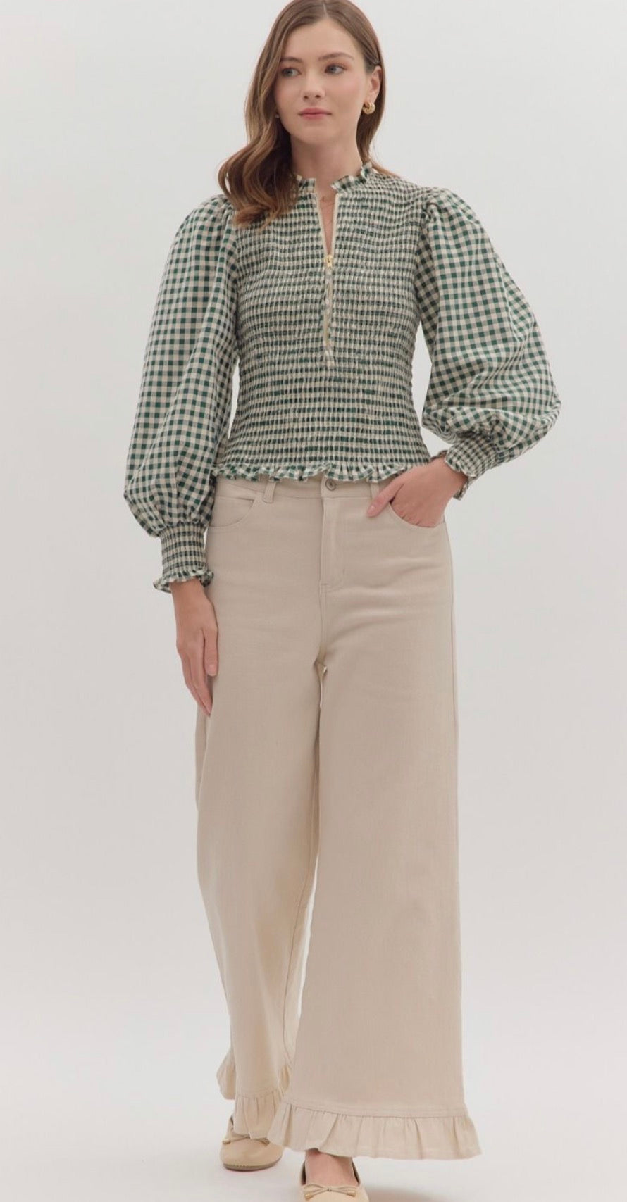 Gingham long puff sleeve top featuring smocked bodice and ruffle hem. Zip closure at front