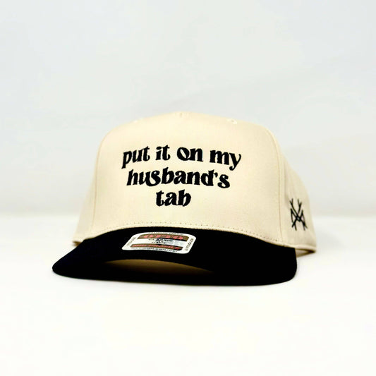 MHC Put it on my Husband's Tab Trucker Hat: Black/Natural Otto