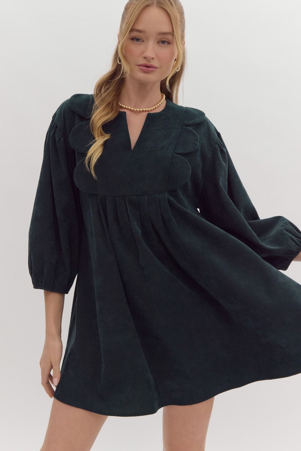 Solid 3/4 sleeve v neck mini dress featuring pockets at side. Oversized scallop detail at bust. Forrest green