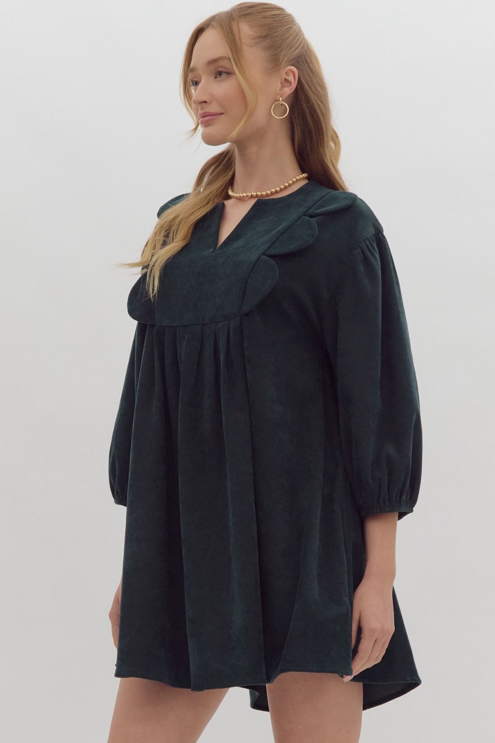 Solid 3/4 sleeve v neck mini dress featuring pockets at side. Oversized scallop detail at bust. Forrest green