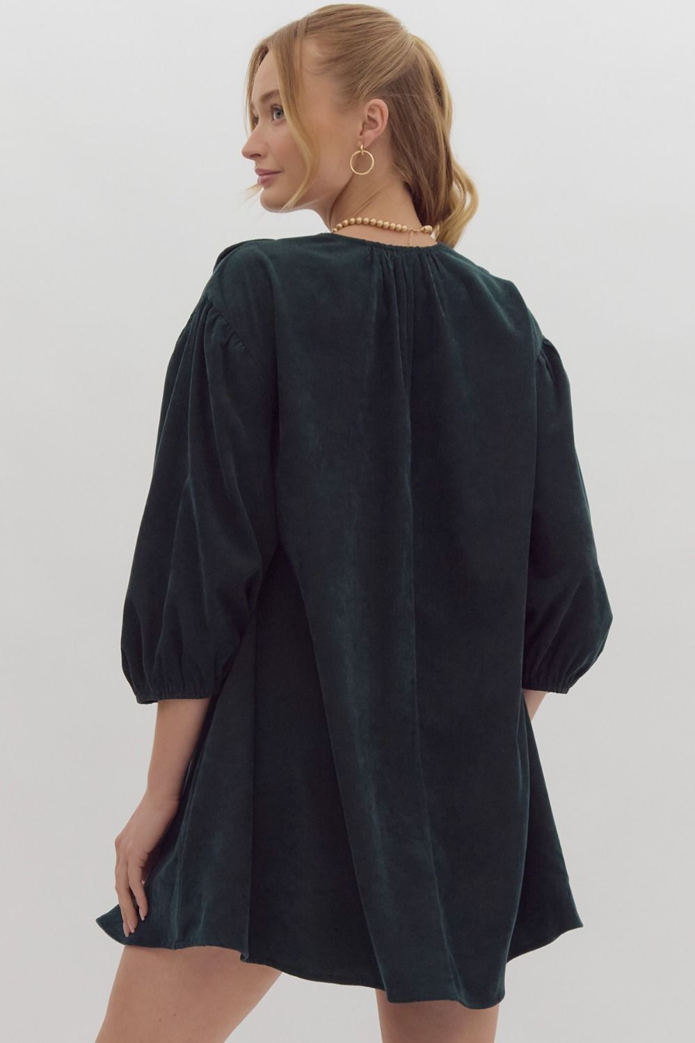 Solid 3/4 sleeve v neck mini dress featuring pockets at side. Oversized scallop detail at bust. Forrest green