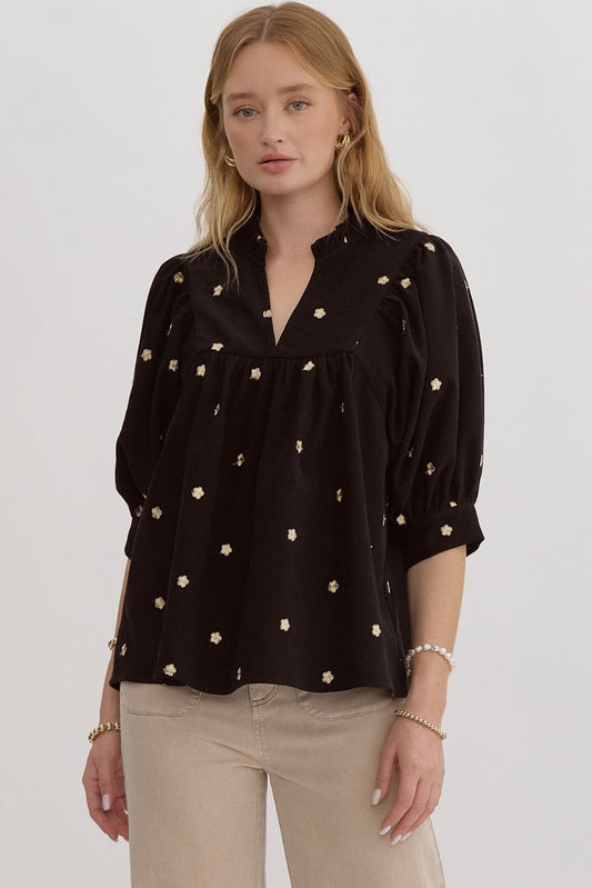 Solid v-neck half sleeve top featuring embroidered florals. Button closure at cuff.