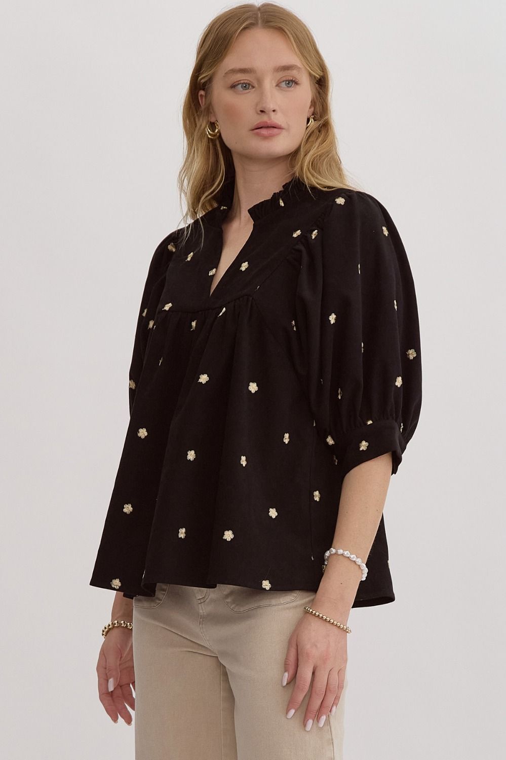 Solid v-neck half sleeve top featuring embroidered florals. Button closure at cuff.